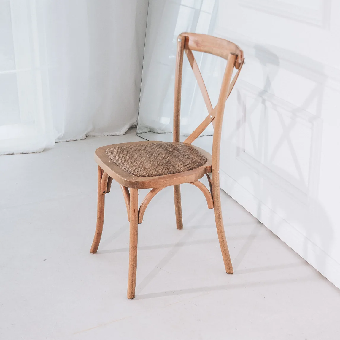 Cross Back Chair aus naturfarbenem Holz mit X-Rückenlehne und Flechtsitz, schräg von vorn.