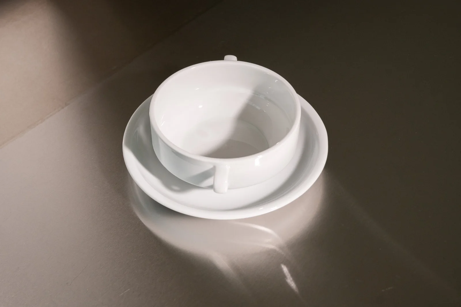 Weiße Delta-Suppentasse mit zwei Henkeln und passender Untertasse. Weitere Ansicht.